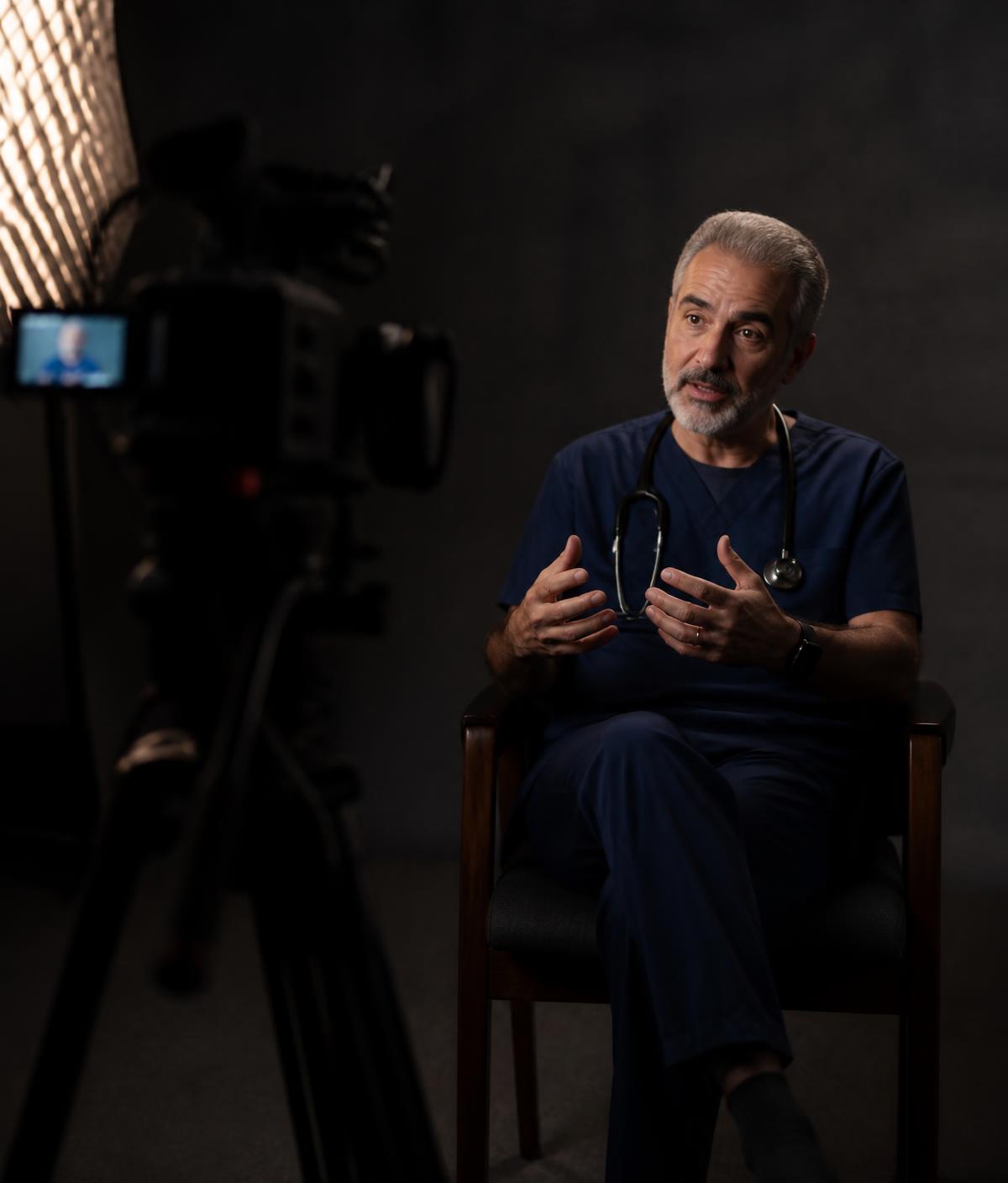 A physician being professionally recorded on camera in a studio